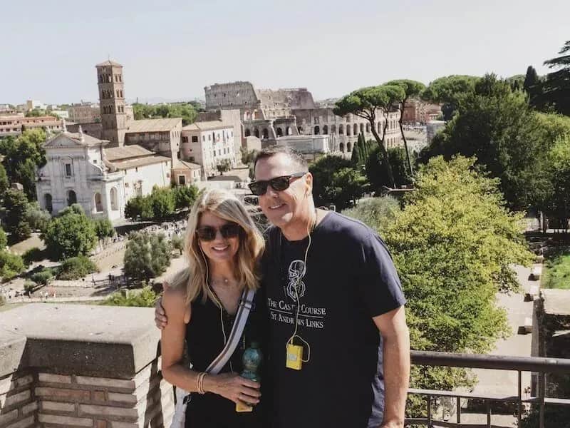 Happy couple enjoying VIP Colosseum tour taking romantic photo with iconic ancient Roman amphitheater and Forum backdrop during Carpe Diem Tours Rome exclusive experience