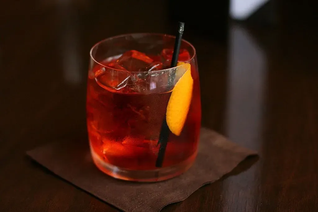 Close-up of a classic Negroni cocktail with an orange peel garnish in a rocks glass.