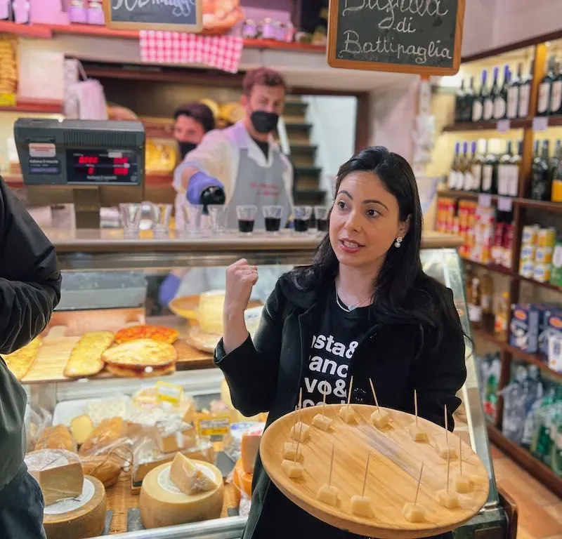 Woman holding a large cheese wheel during a Carpe Diem cheese and food tour in Trastevere, Rome
