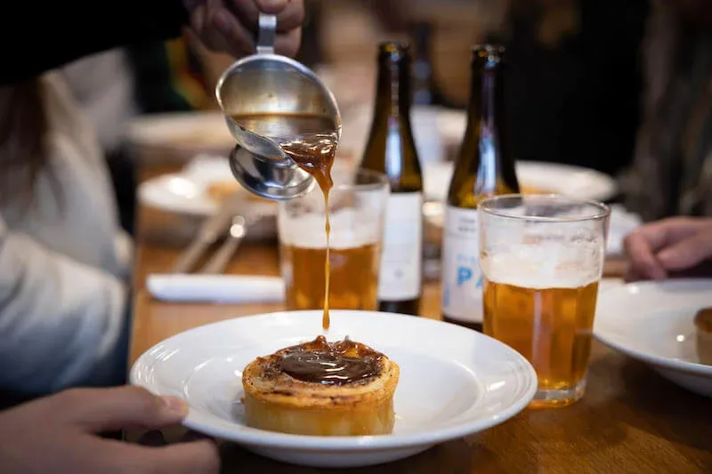 Pouring gravy over a hearty steak and blackheart stout pie