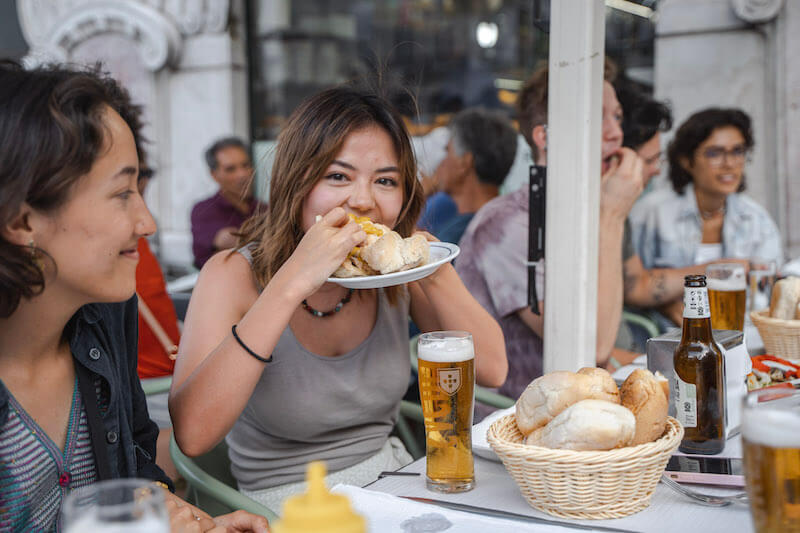 Girl eating bifana sandwich on Carpe Diem Tours' Lisbon Food Tour