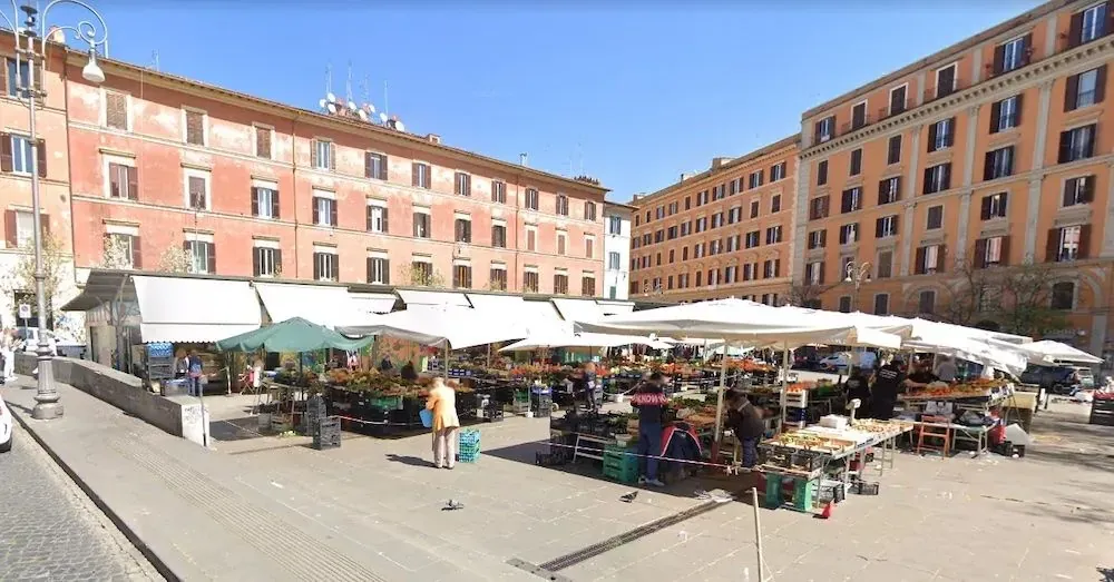 Piazza San Cosimato market square in Trastevere, Rome, with stalls and surrounding buildings on a sunny day