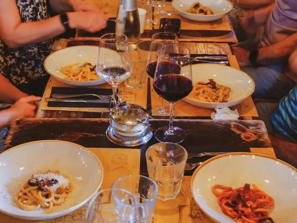 Tourists enjoying authentic Italian pasta tasting experience with wine during Carpe Diem Tours Rome Trastevere food tour culinary adventure