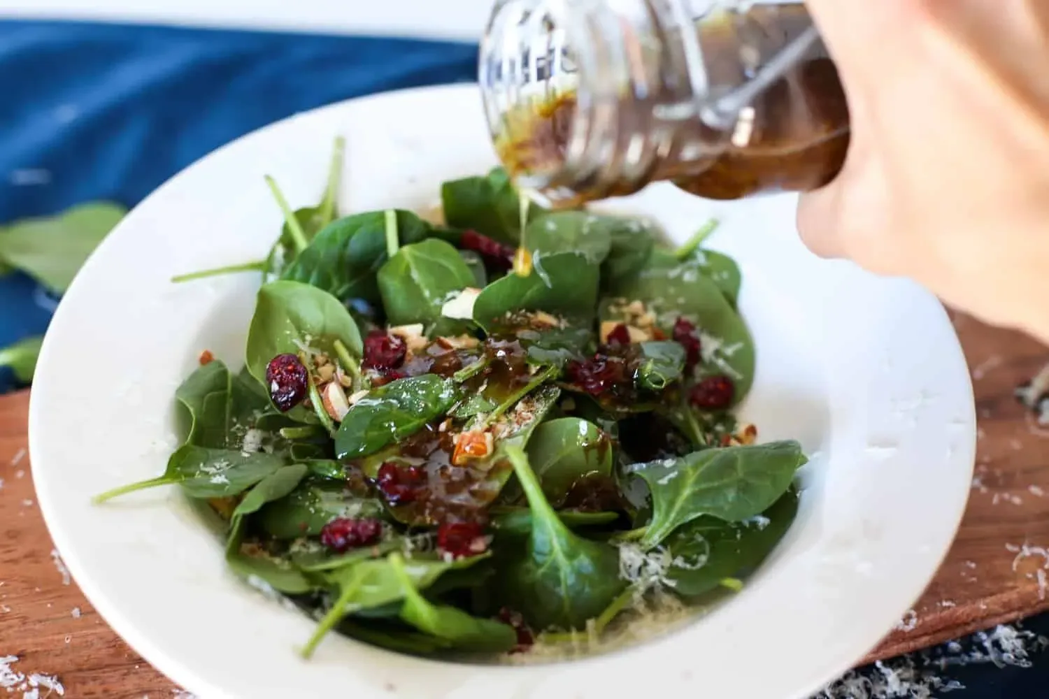 A hand drizzling balsamic vinegar over a fresh salad, demonstrating the culinary use of aged balsamic vinegar in traditional Italian cuisine.