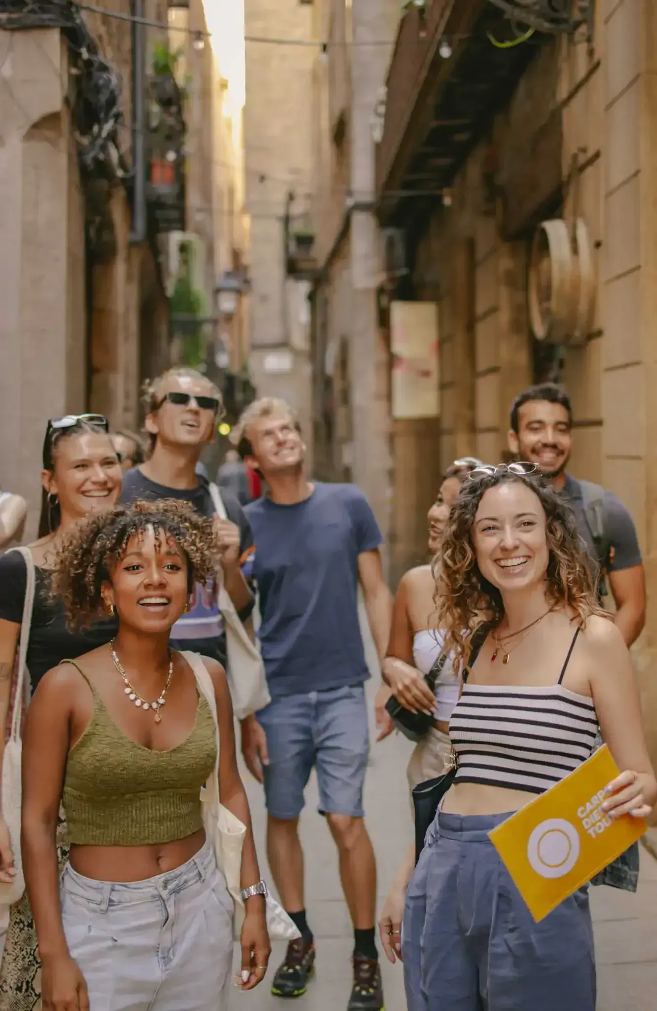 Happy tour group walking through narrow medieval street in Barcelona's Gothic Quarter