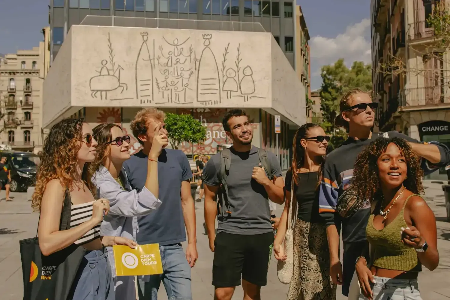 Tour group at Plaça Reial viewing street art mural with historic Barcelona buildings in background
