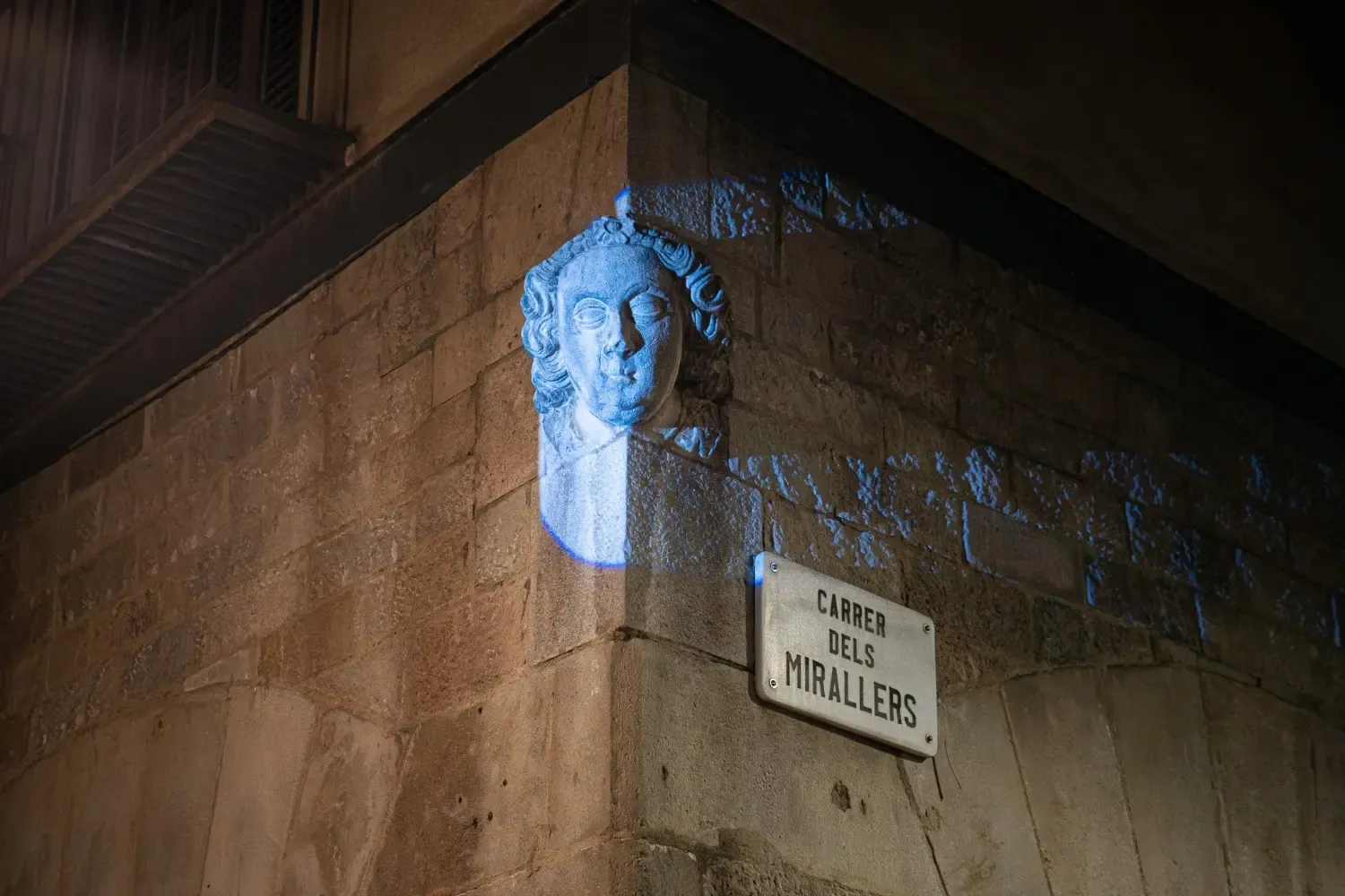 A close-up of a mysterious blue-illuminated sculptural head on a Gothic Quarter street in Barcelona, a notable paranormal landmark featured on the ghost tour route.