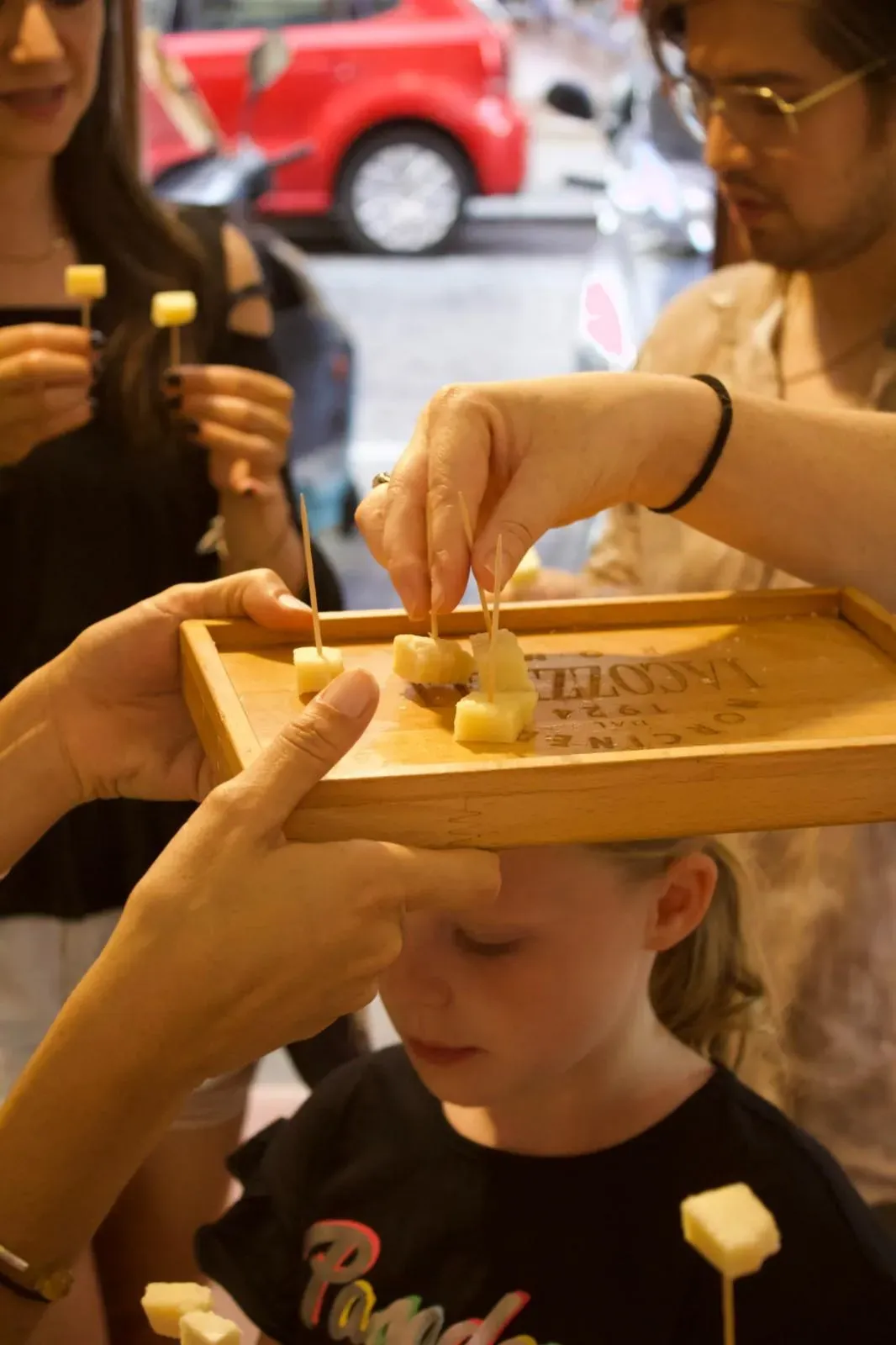 A young child happily eating a cube of Italian cheese from a wooden tasting board during a family-friendly Rome food tour experience.