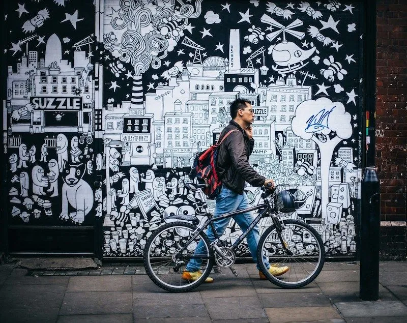 Person riding a bicycle in front of a graffiti-covered wall