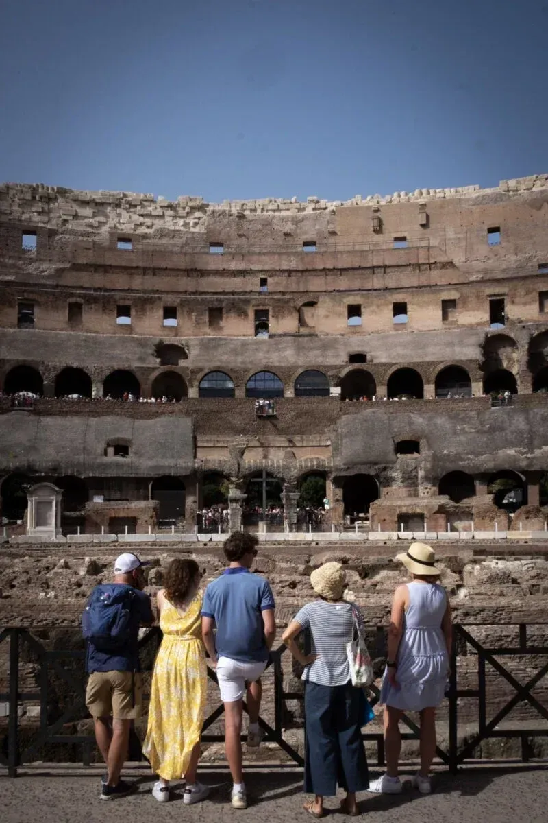 Tourists walking the historic gladiator path on the Colosseum arena floor