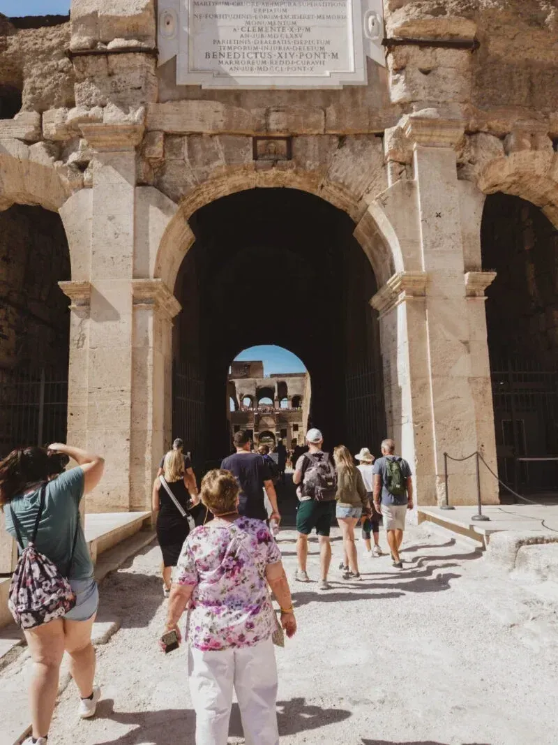 Visitors standing on the Colosseum arena floor experiencing ancient Roman history
