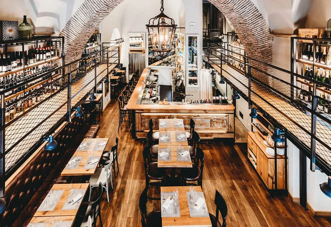 Elegant two-level fine dining restaurant with an extensive wine cellar and rustic wooden tables.