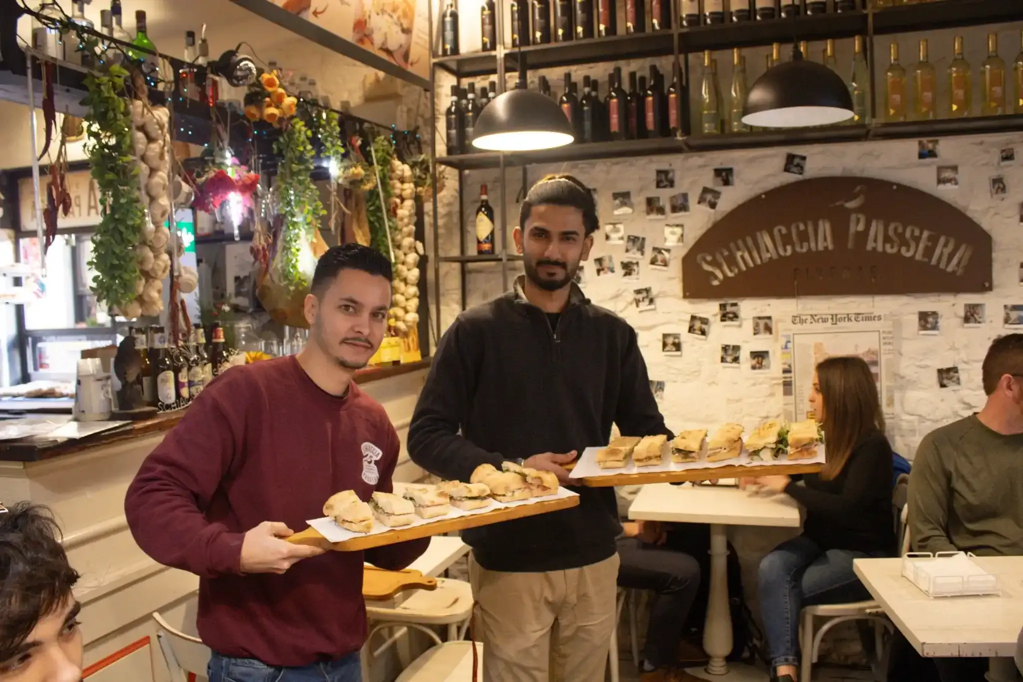 Group of tourists enjoying wine and food tasting at a Florence food tour restaurant with decorated walls and hanging garlic