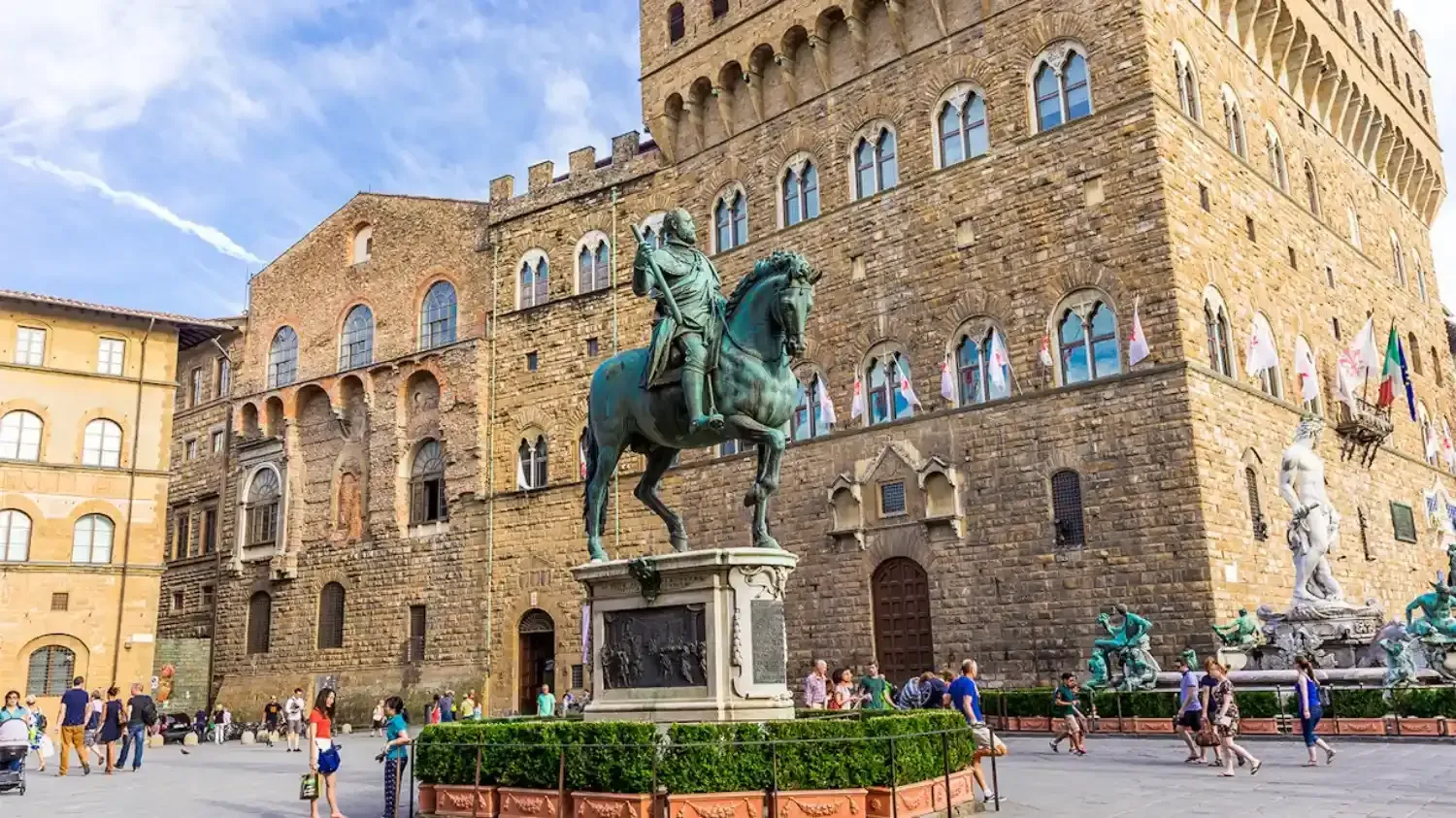 Palazzo Vecchio Renaissance palace with green patina equestrian statue in historic square with tourists and historic architecture