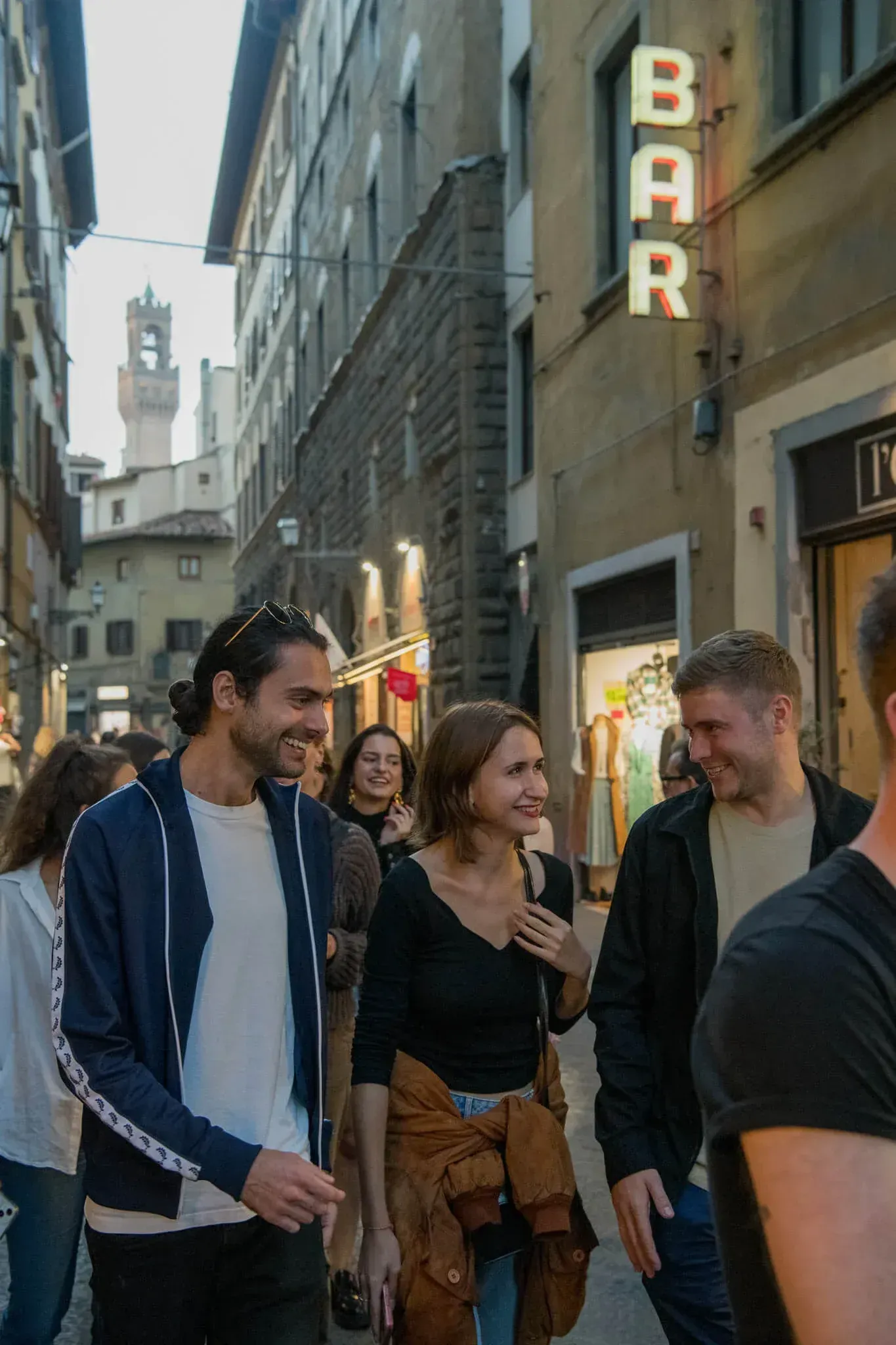 Group of tourists walking through charming Florence street with historic architecture and evening street lights on private walking tour