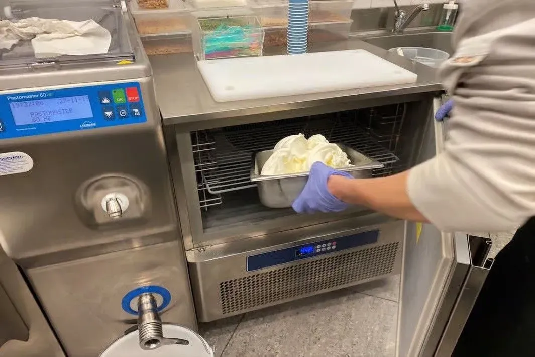 A chef placing freshly made gelato into a professional freezing machine during a hands-on gelato-making masterclass in Florence, showcasing the final freezing step of authentic Italian gelato production.