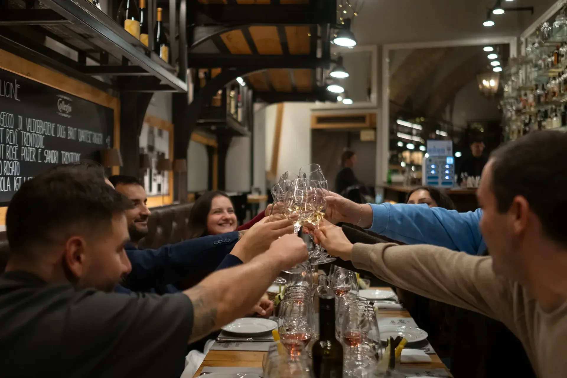 A group of friends making a celebratory toast with glasses of white wine at a tasting.