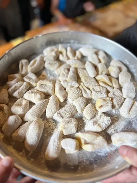 A white bowl filled with freshly made pasta shapes during a traditional Tuscan cooking class workshop.