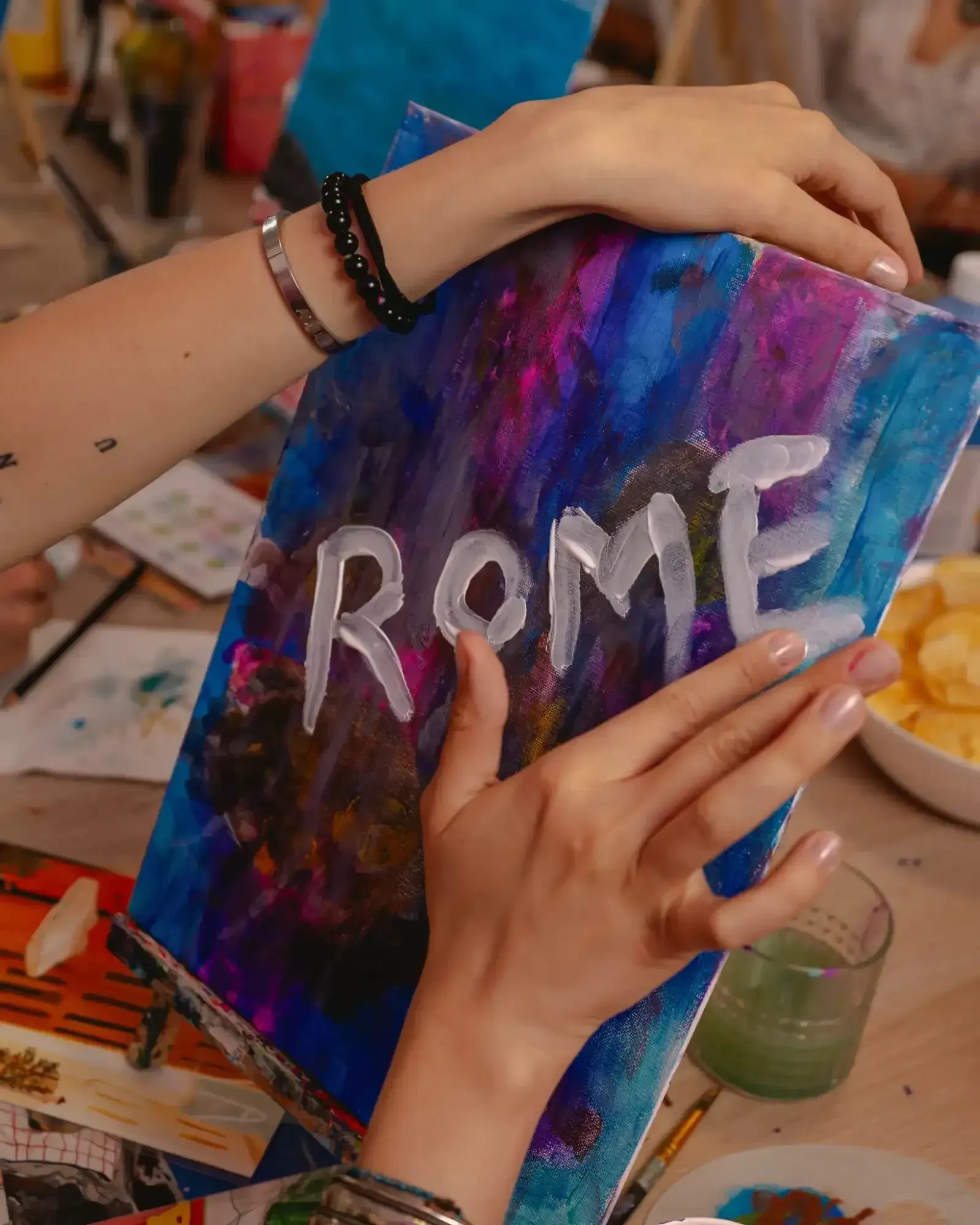 Professional art instructor teaching painting techniques to class participants in Rome