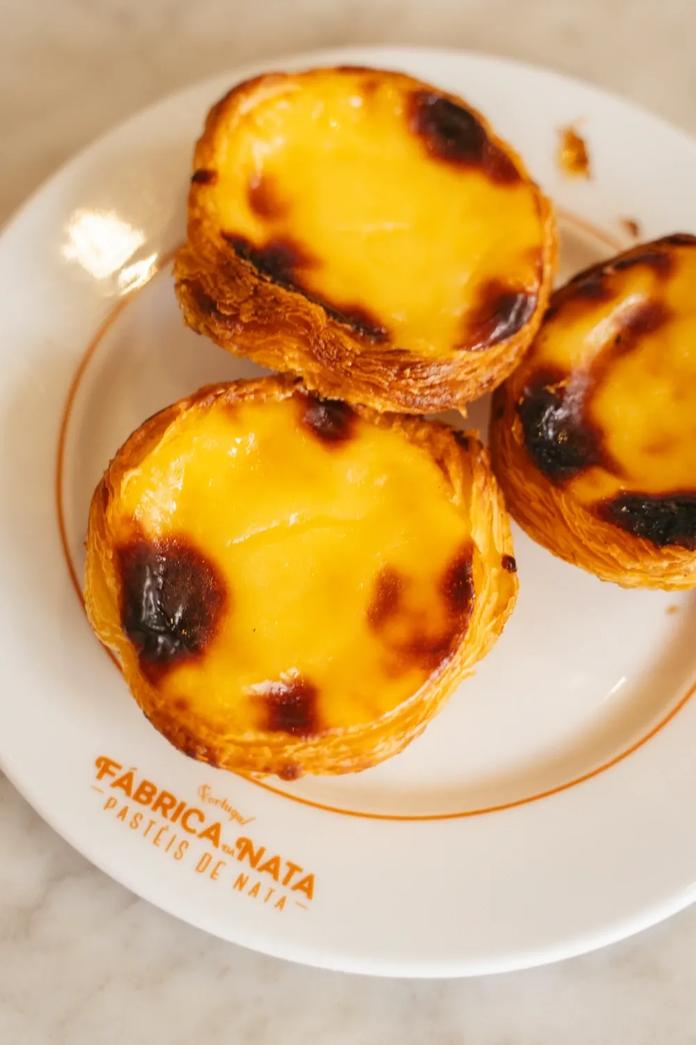 Three pastéis de nata served on a Fábrica da Nata plate during the Lisbon Food Tour