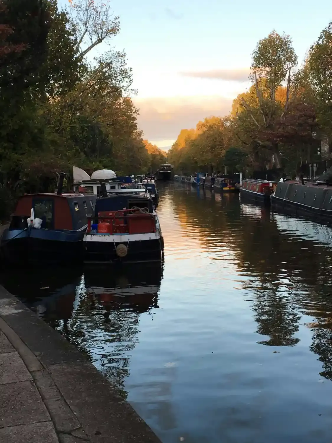 Livorno canal with traditional boats moored along waterway surrounded by autumn trees and historic buildings