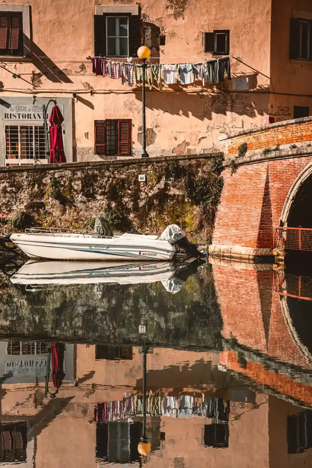 Historic Livorno harbor with terracotta buildings boats and water reflection showing traditional Italian architecture