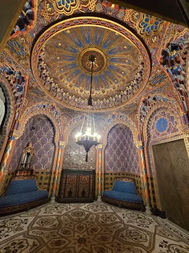 Ornate museum ceiling dome with gold leaf decorations blue walls and classical architectural patterns in historic room