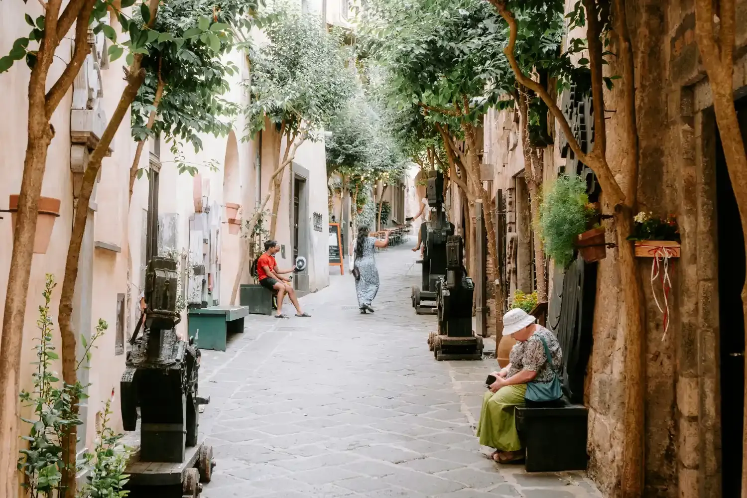 Medieval street in Orvieto with tree-lined alley historic buildings and local residents enjoying the town