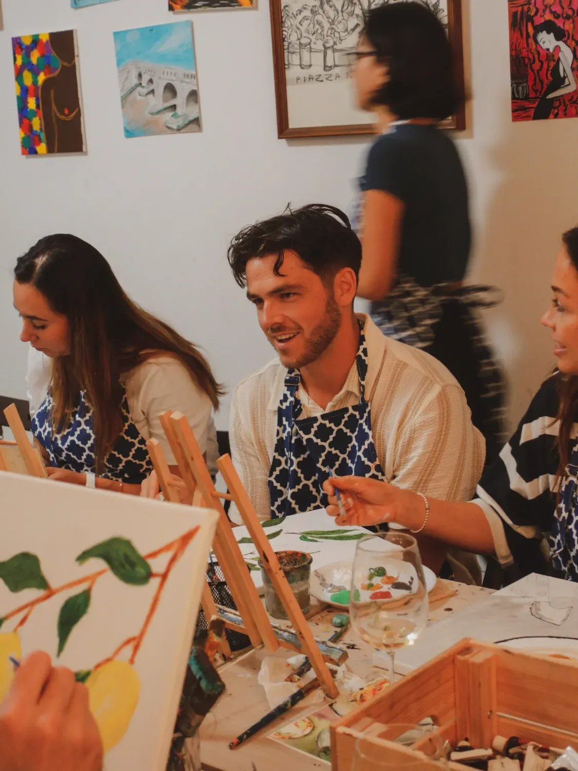 Group of happy participants gathered together with their finished paintings displayed on easels