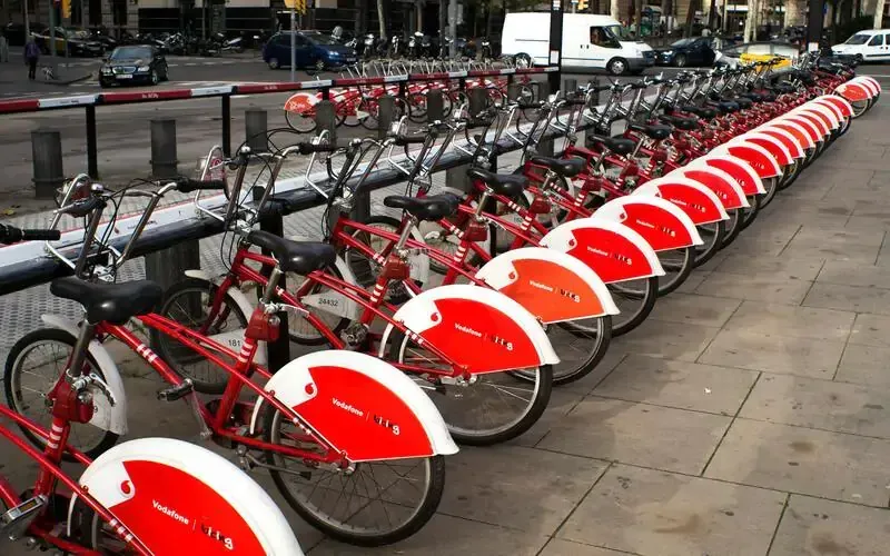 Row of red city bikes in urban bike sharing system showcasing sustainable transportation and eco-friendly travel options during Carpe Diem Tours city exploration and cultural sightseeing experience