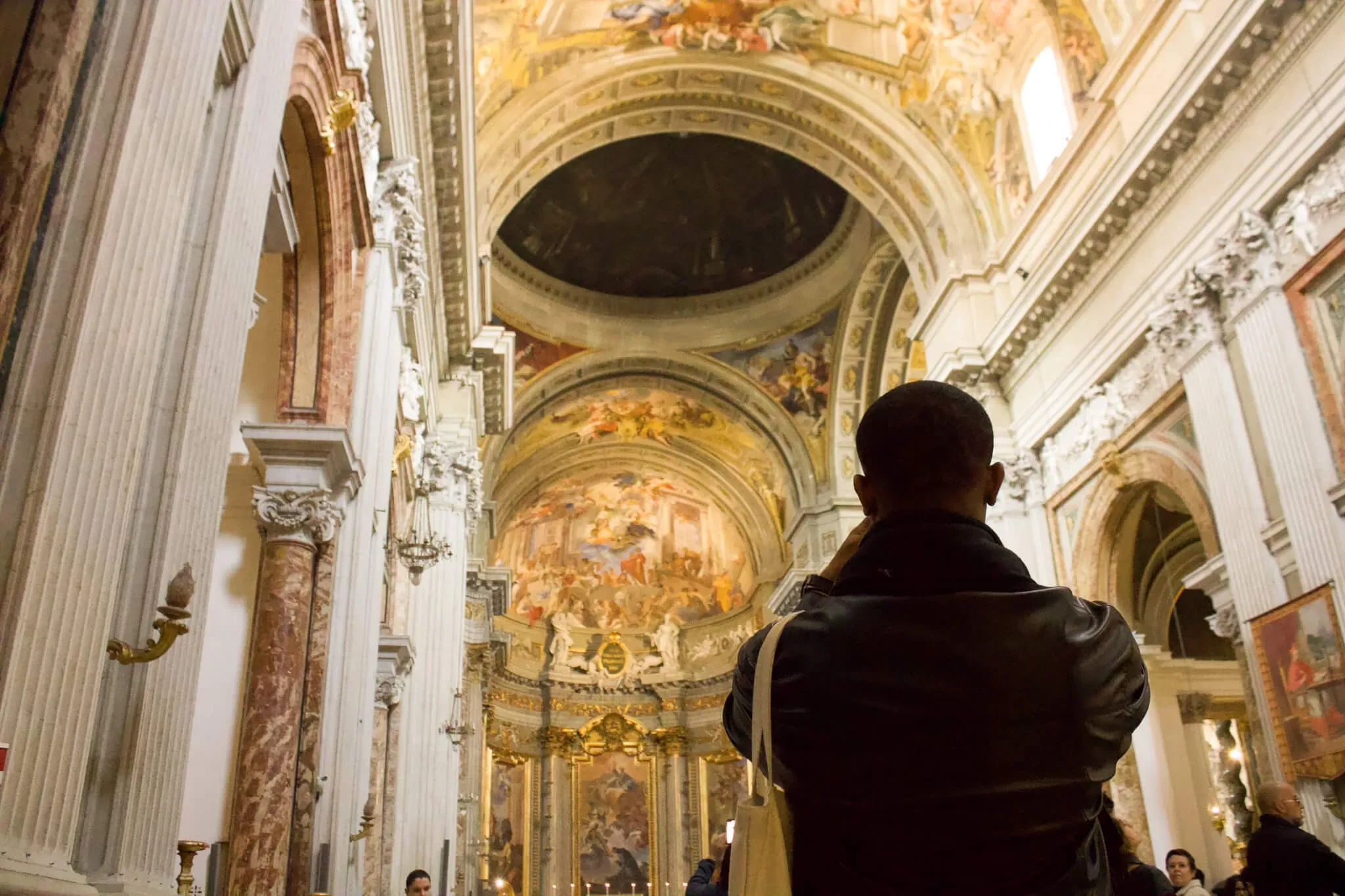 Tourist admiring ornate ceiling frescoes and baroque architecture inside historic Roman church during Carpe Diem Tours