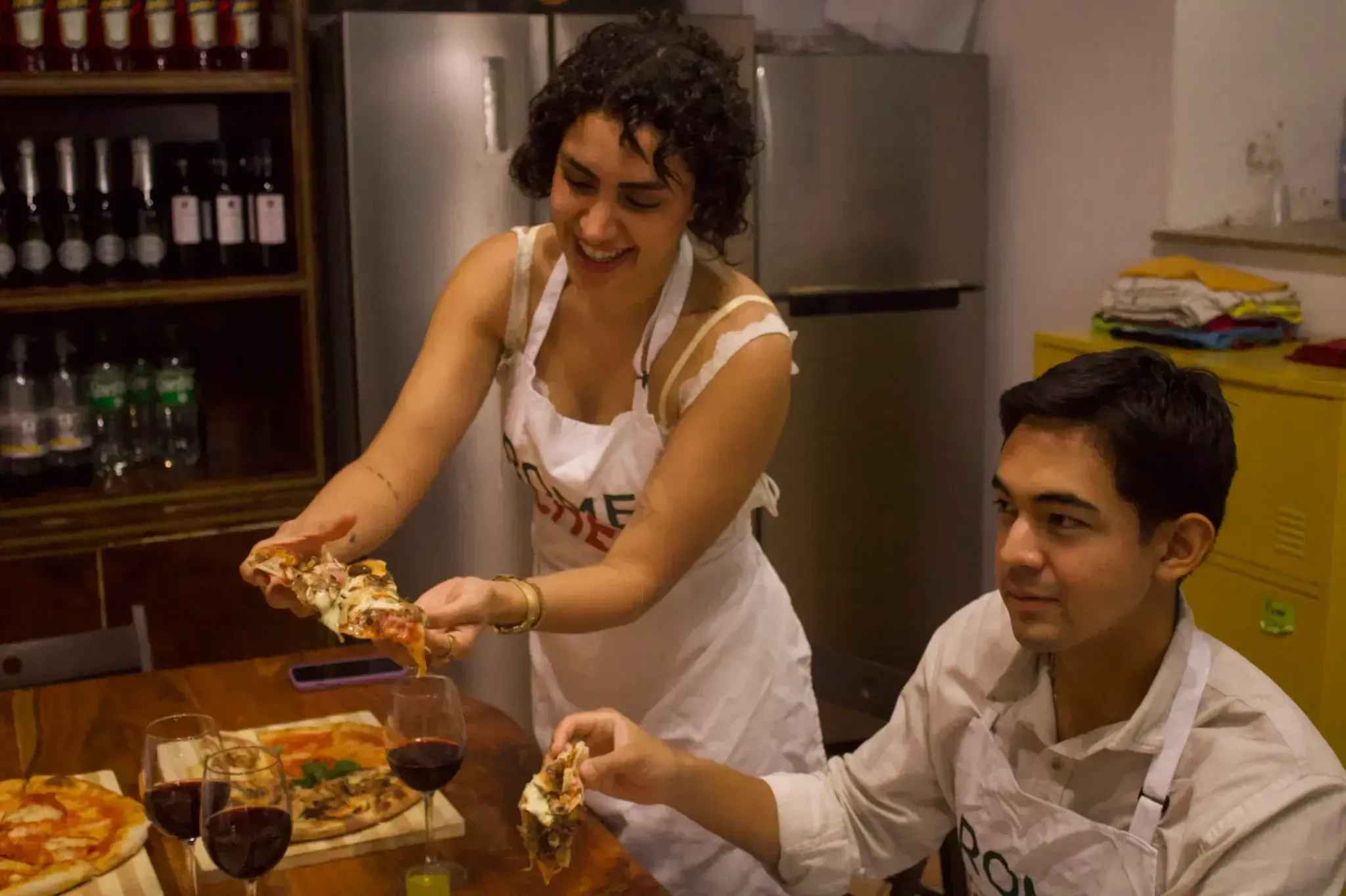 Woman in Rome with Chef apron smiling while serving a freshly baked pizza slice to a participant