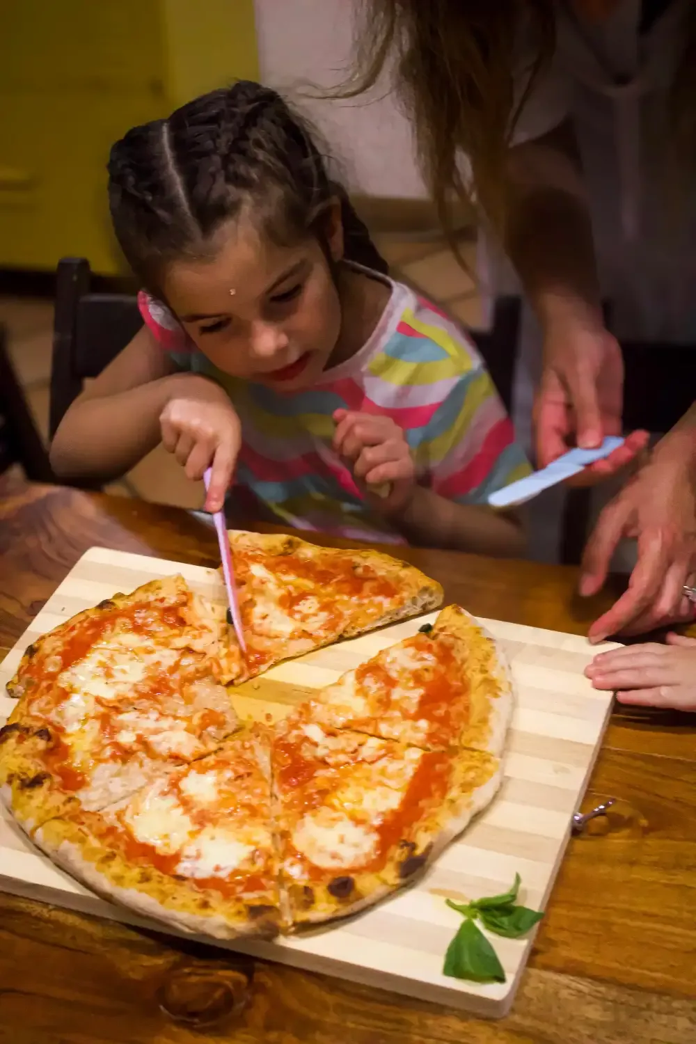 Young child happily eating a slice of freshly made Margherita pizza with mozzarella and basil