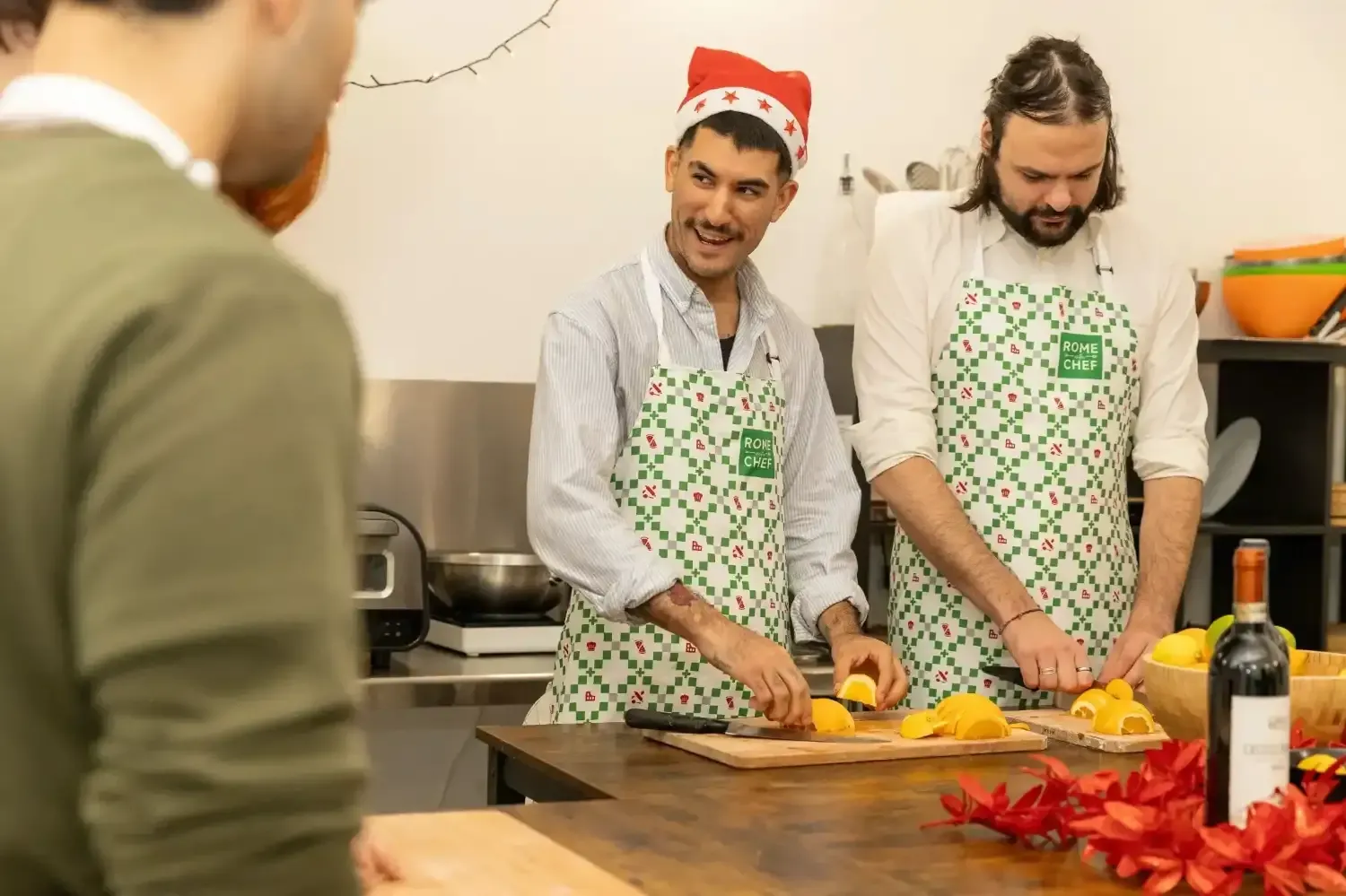 Male instructor in Rome with Chef apron and Santa hat demonstrating orange slicing technique to participants