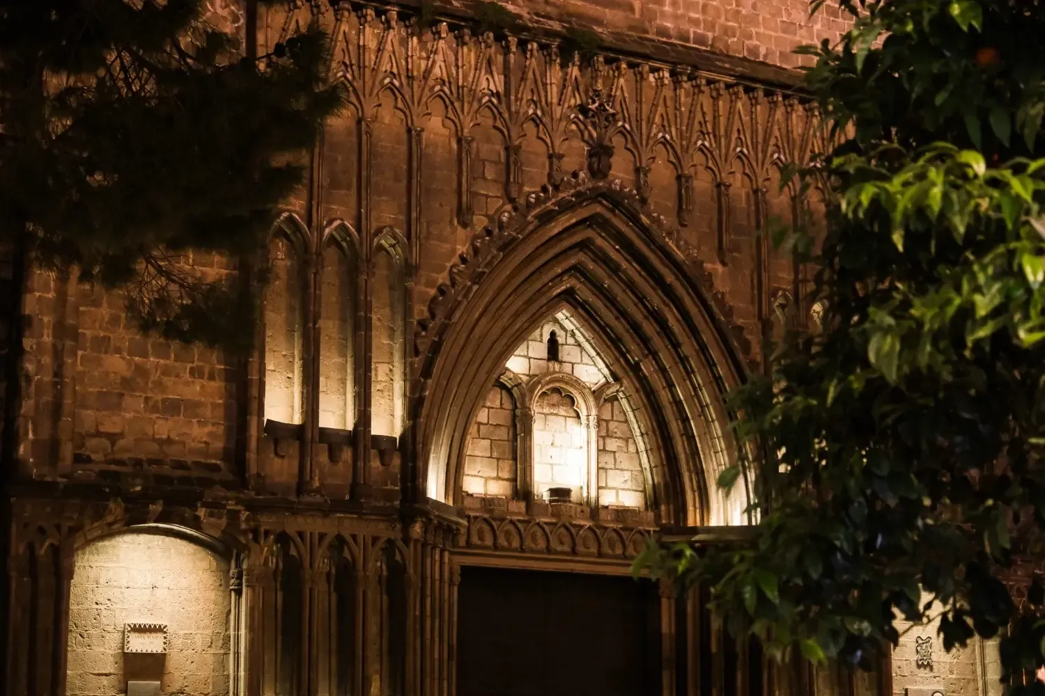 Plaça Sant Felip Neri beautifully illuminated at night with festive decorations and atmospheric street lamps, one of the most tragic sites featured on the Barcelona ghost tour with historical significance.