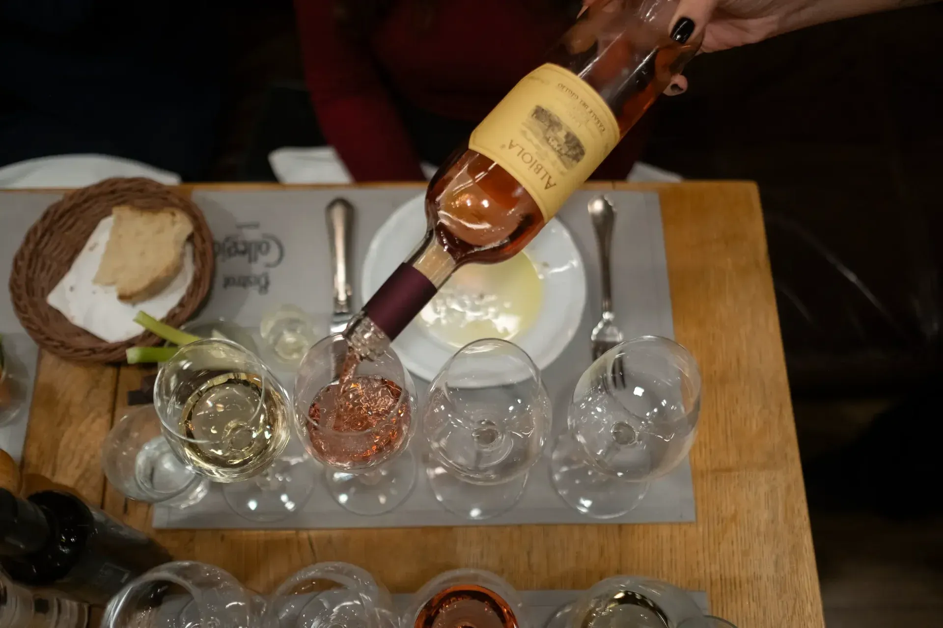 Pouring a glass of rosé wine into a tasting flight at a wine bar.