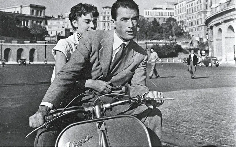 Classic black and white photo inspired by Roman Holiday, showing a couple on a Vespa scooter in Rome, relevant for Vespa tours