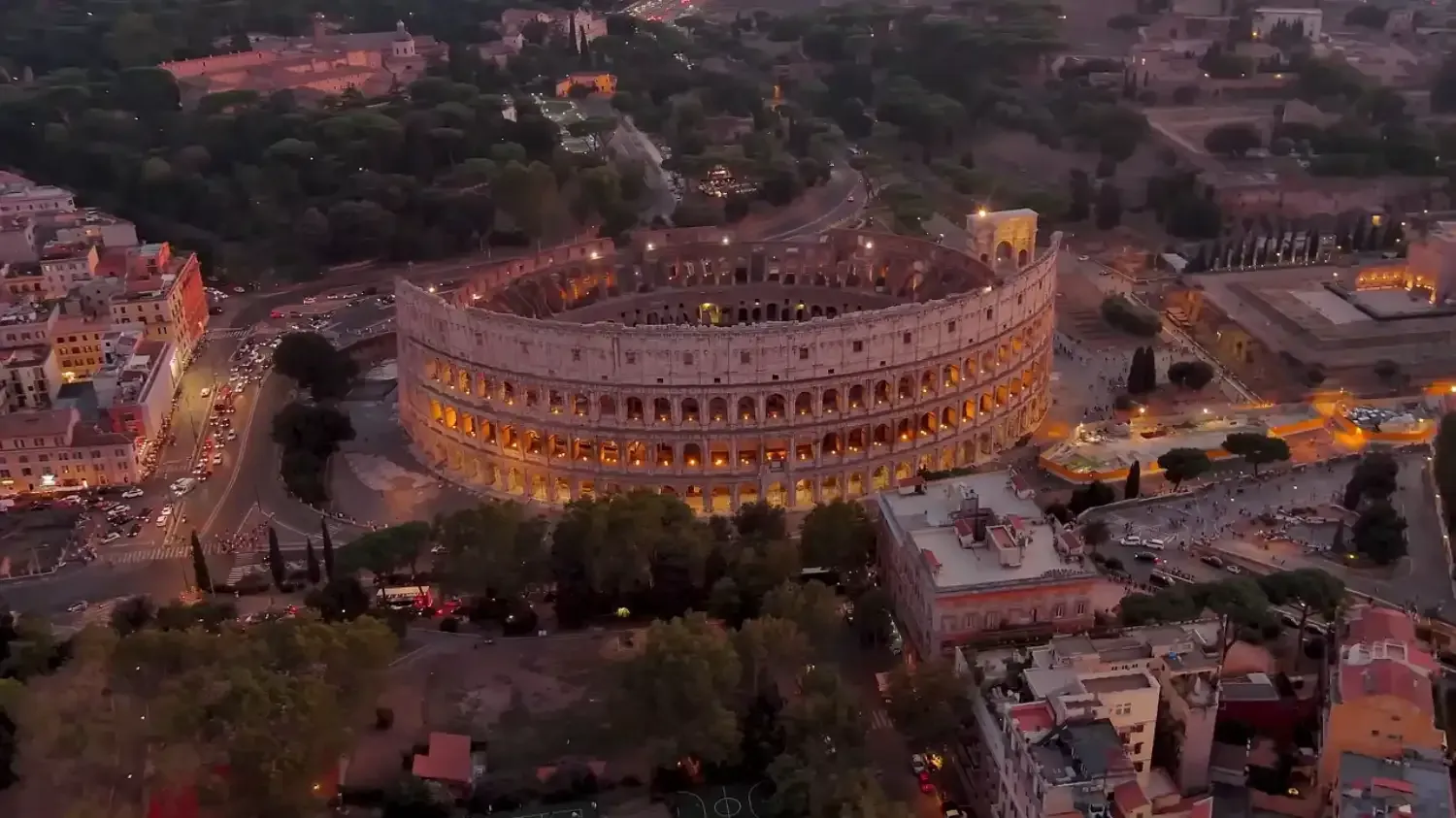 Iconic Colosseum amphitheater lit up at night with tourists exploring the historic Roman landmark
