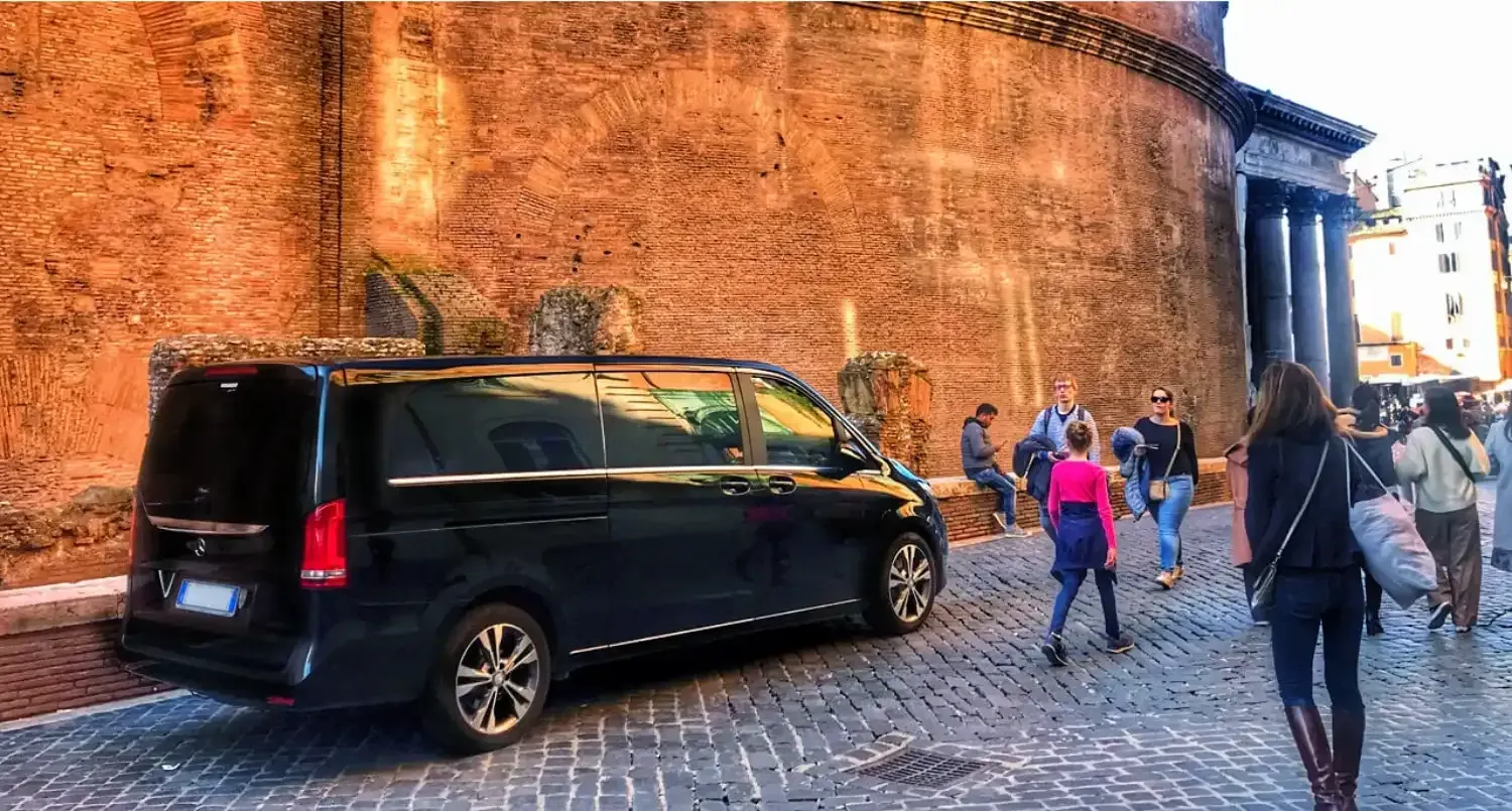 Black Mercedes luxury vehicle parked at historic Rome landmark with tourists exploring the ancient architecture