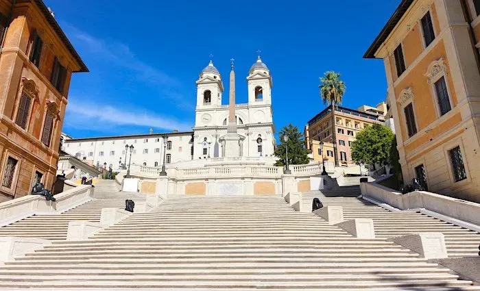 Spanish Steps historic plaza during daytime with white church, Renaissance architecture, and tourists enjoying the iconic landmark