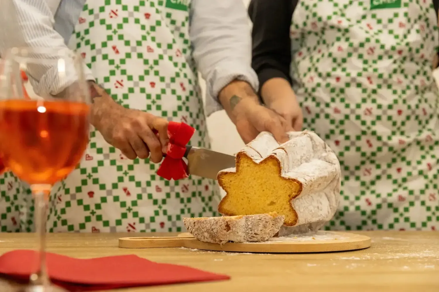 Slicing traditional star-shaped Italian Christmas cake with Aperol Spritz cocktail during holiday cooking class