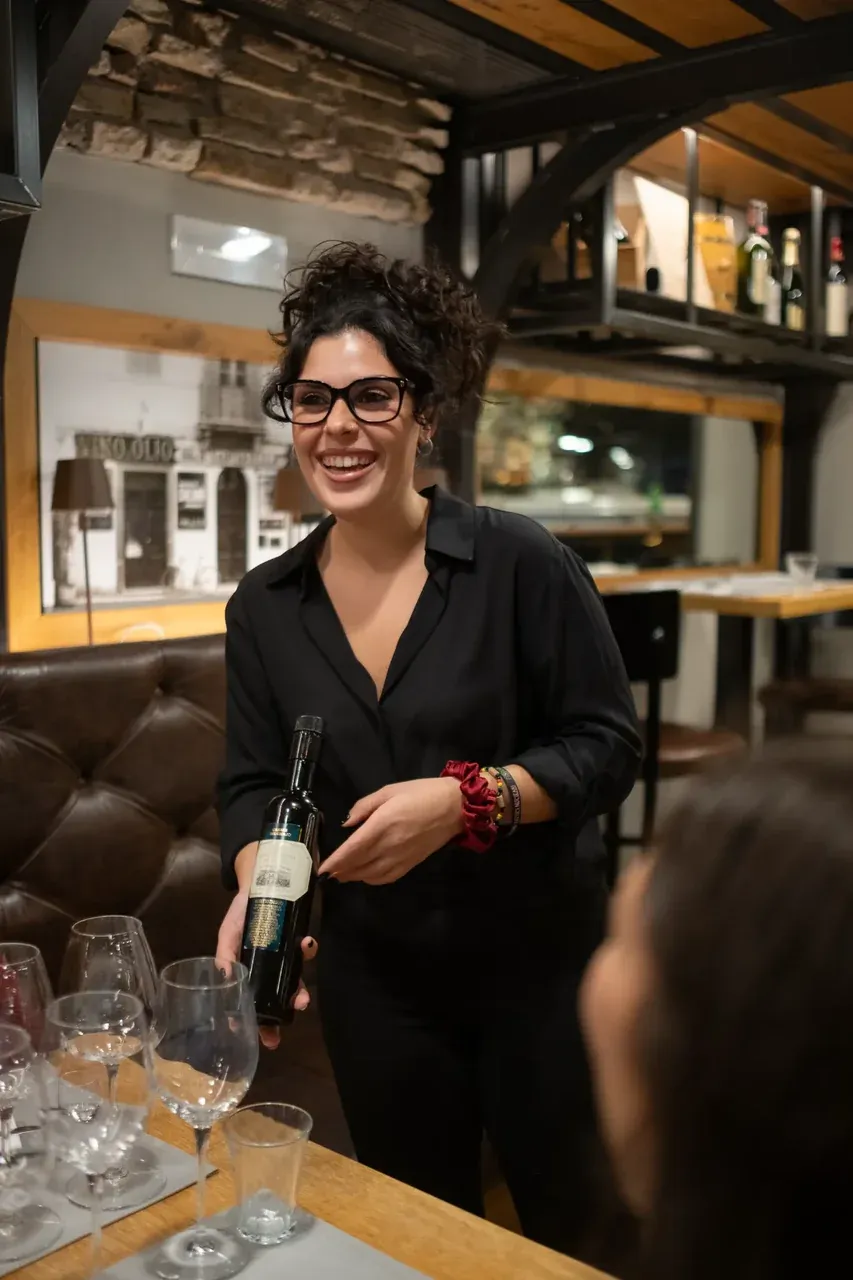 A professional sommelier presenting a bottle of fine Italian wine to guests at a restaurant.