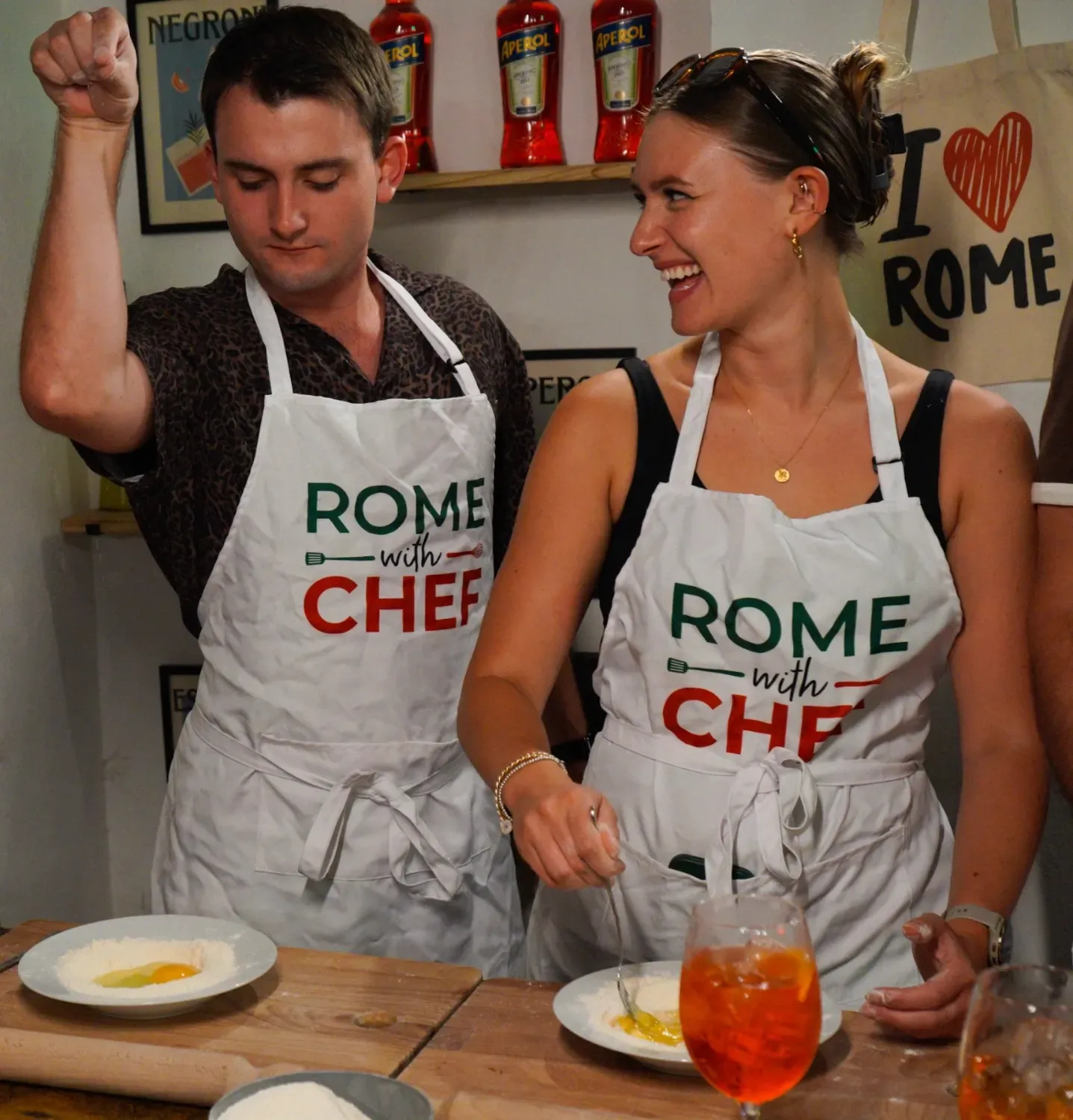 Happy couple in Rome with Chef aprons celebrating with Spritz cocktails and plates of fresh pasta during the cooking class
