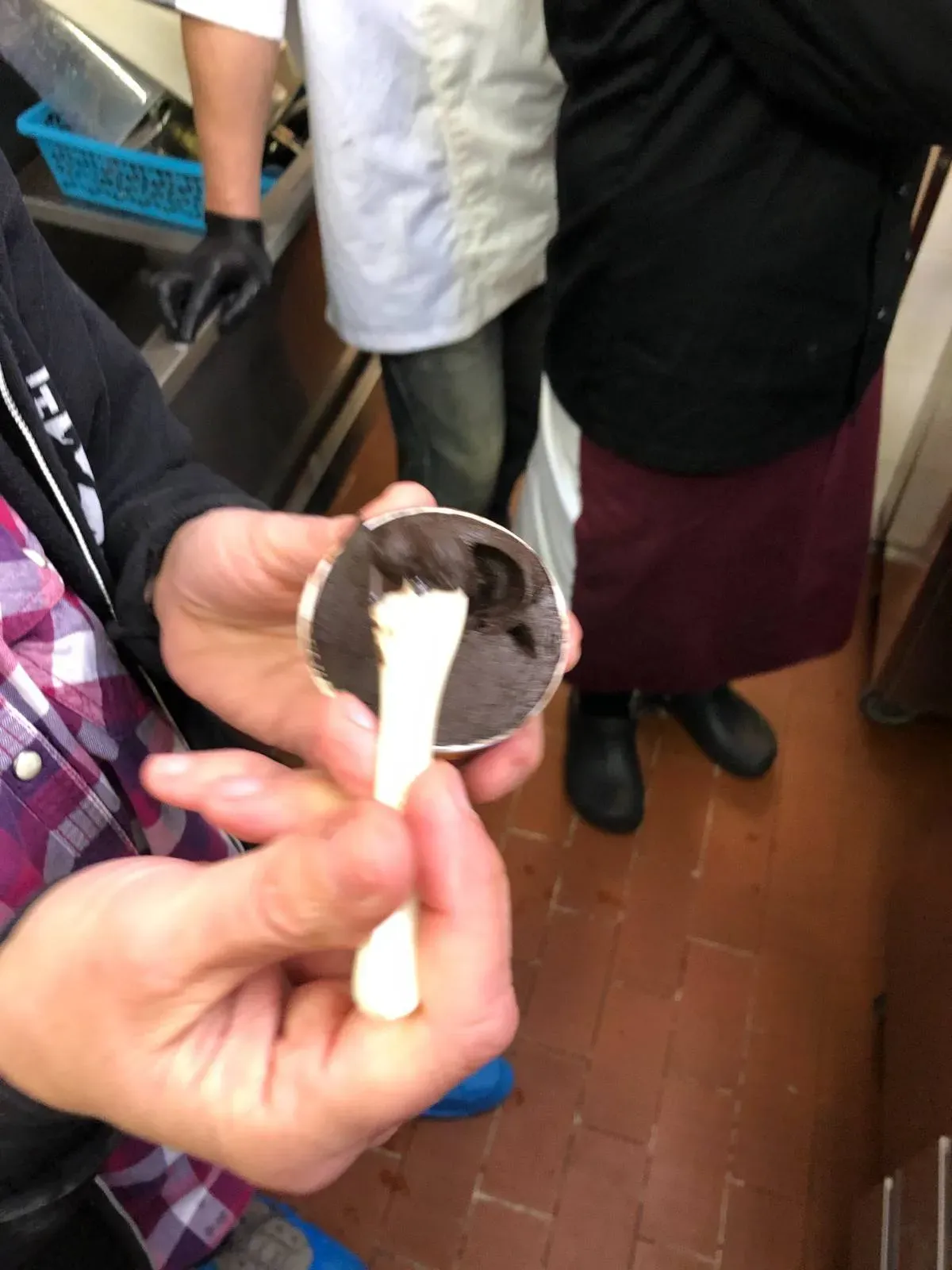 A participant holding a spoon with a taste of their handmade chocolate and vanilla gelato creation during a gelato-making masterclass in Florence, enjoying the fruits of their hands-on experience.
