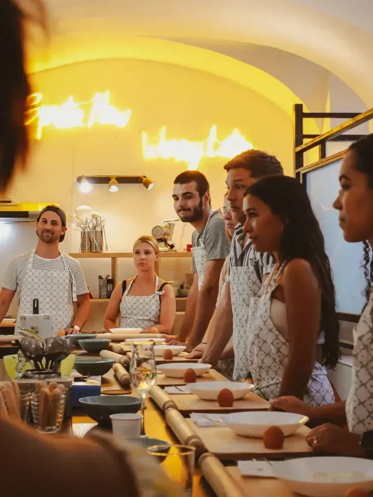 Group of people gathered around a table, enjoying a large tiramisu dessert.