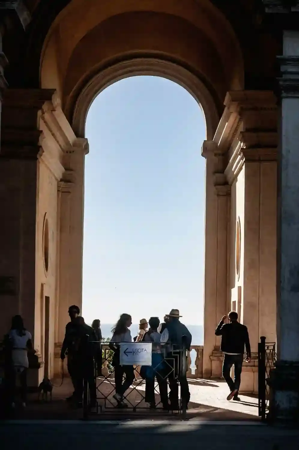 Tourists viewing from Villa d'Este archway with dramatic landscape vista and Mediterranean sea view in distance
