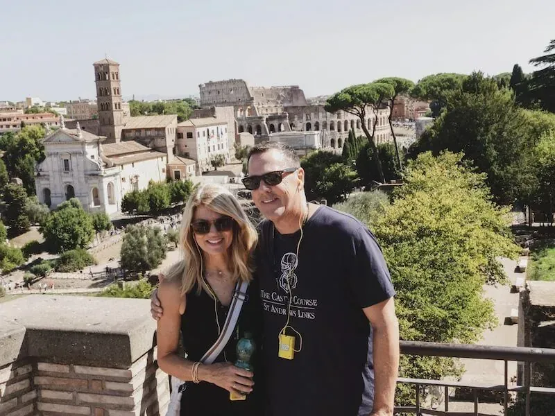 Happy couple enjoying VIP Colosseum tour taking romantic photo with iconic ancient Roman amphitheater and Forum backdrop during Carpe Diem Tours Rome exclusive experience