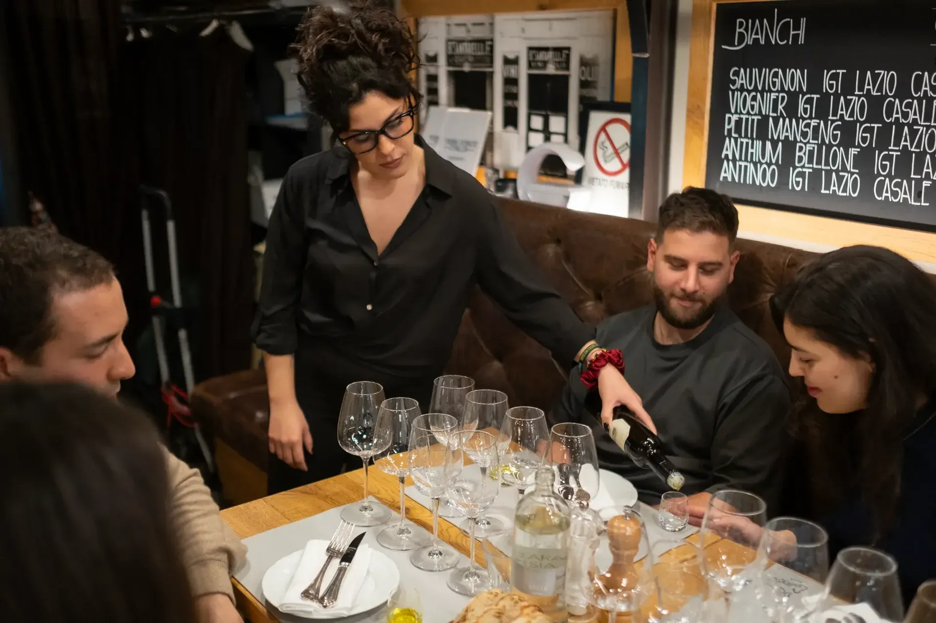 A sommelier pouring wine for guests during an intimate wine tasting session.